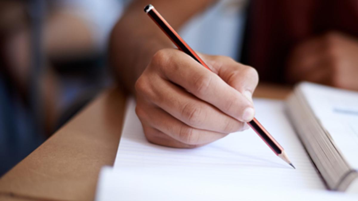 Closeup shot of a young man writing on a note pad